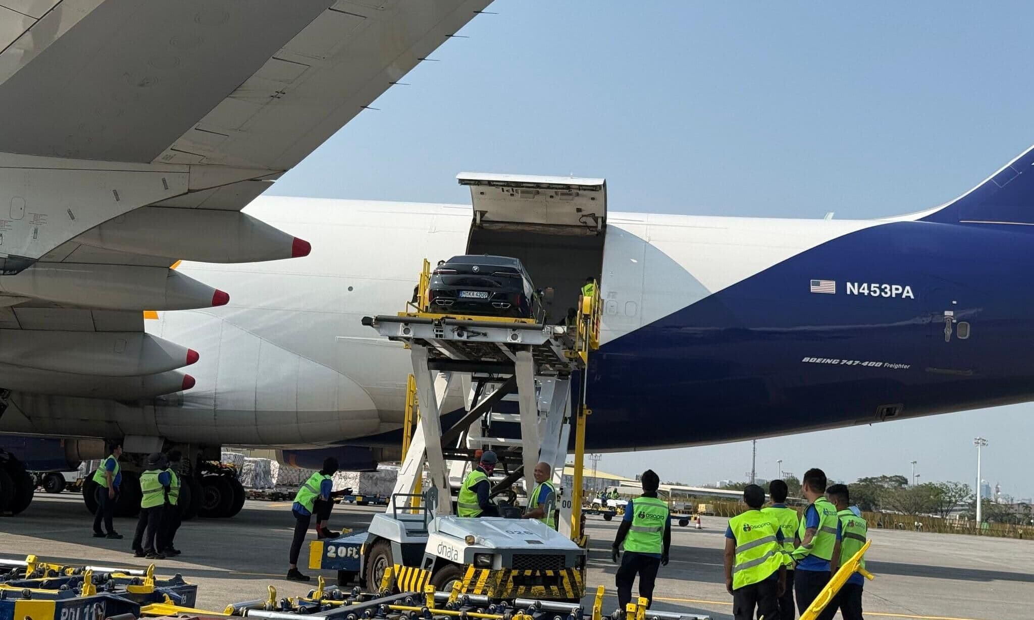 Transporte aéreo Vehículo de lujo en una plataforma de carga junto a la bodega de un Boeing 747 de Atlas Air